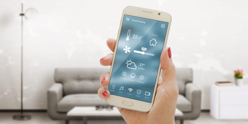 A woman uses her phone's smart home app to track energy usage & save money on her bills.