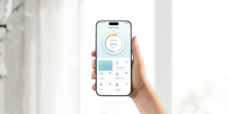 Person using a smartphone to adjust AC temperature, illustrating smart climate control for home comfort and savings.