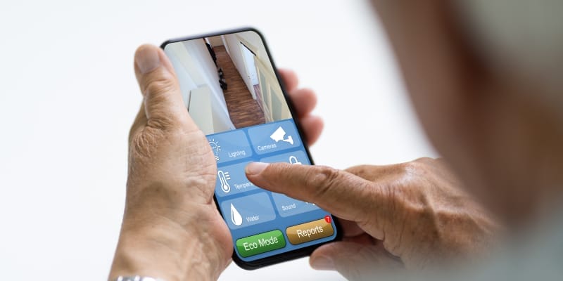 Elderly person using a smart home app on a smartphone to control home devices.